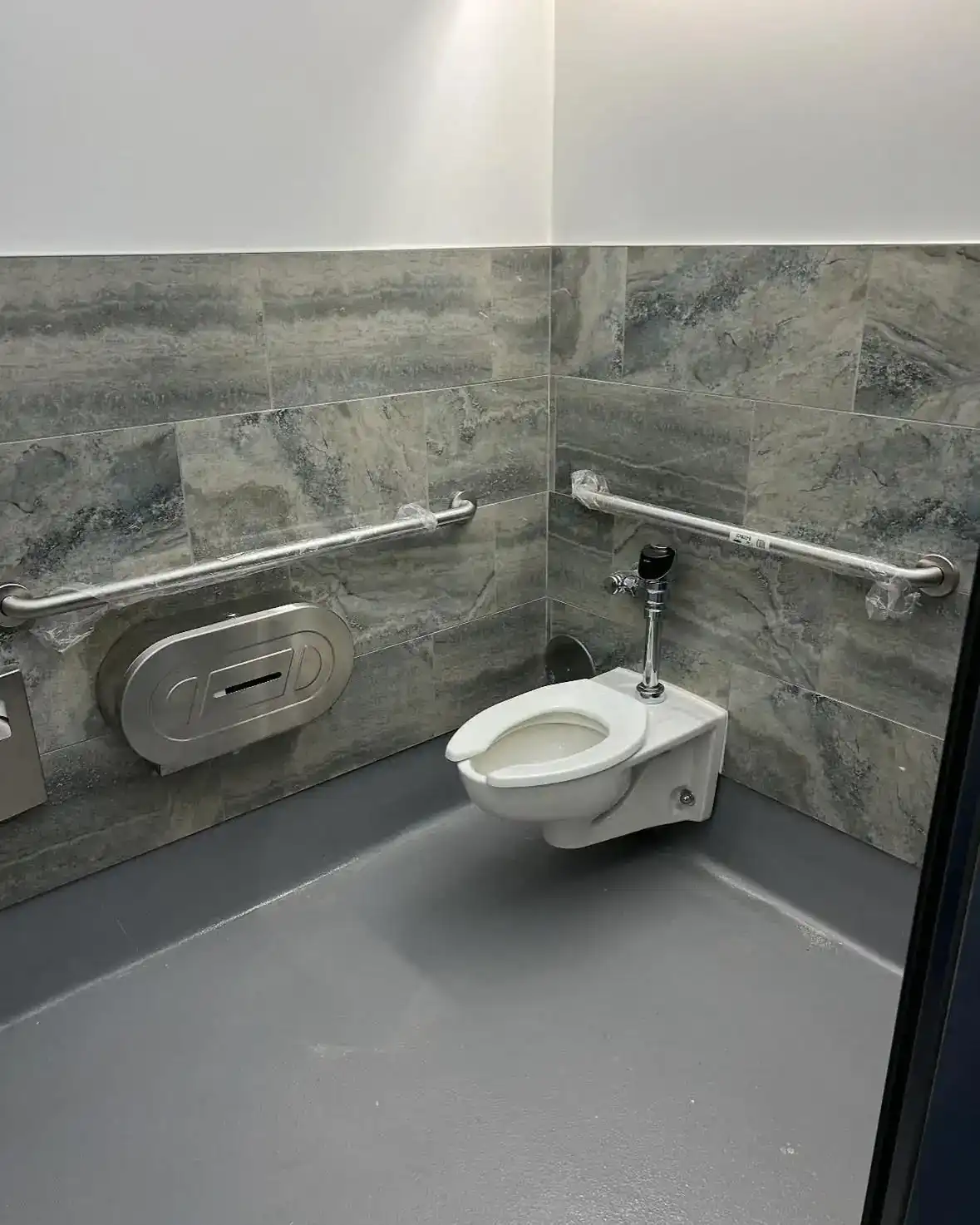 Renovated accessible restroom with grab bars and stone tile