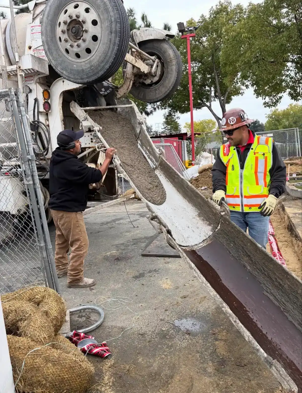 Lopez crew guiding concrete down a mixer chute into a new footing