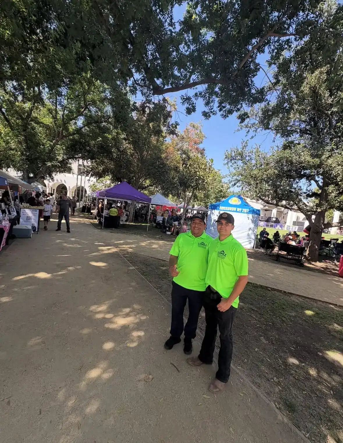 Two Lopez crew members in company shirts at a community street fair