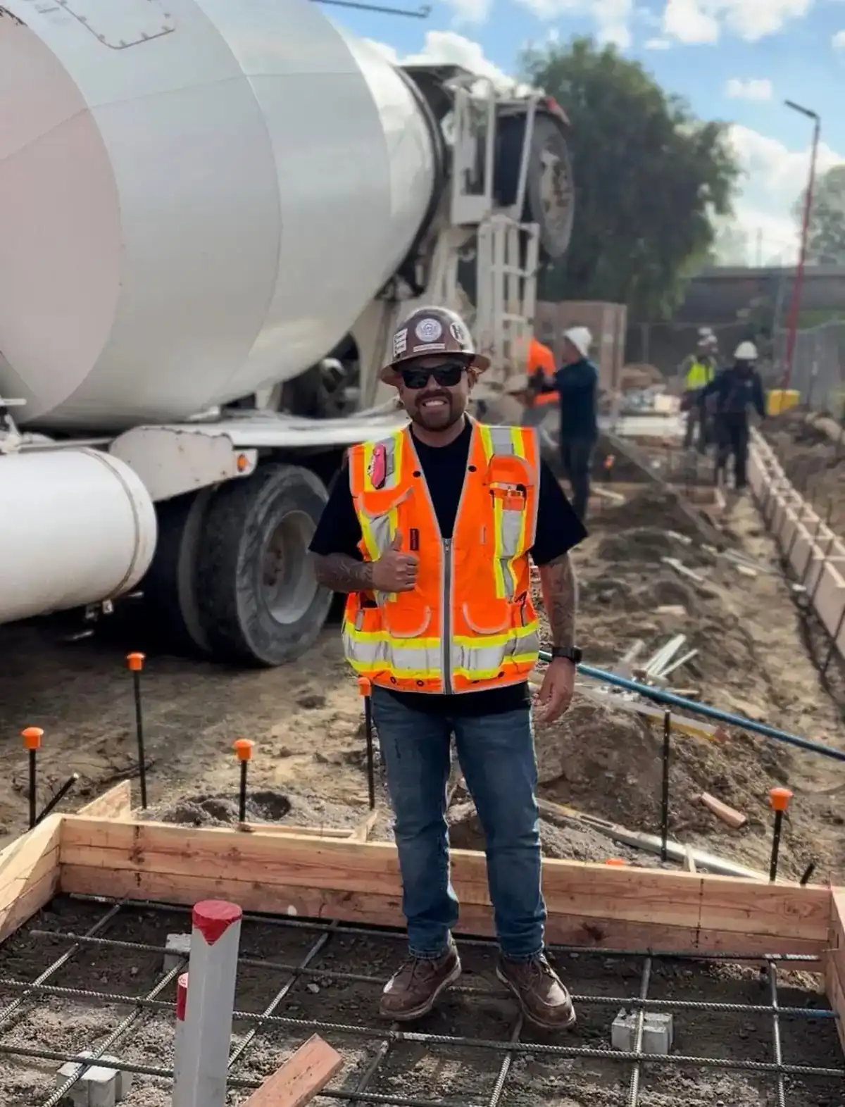 Lopez foreman standing over a formed and rebar-tied footing as a concrete mixer arrives