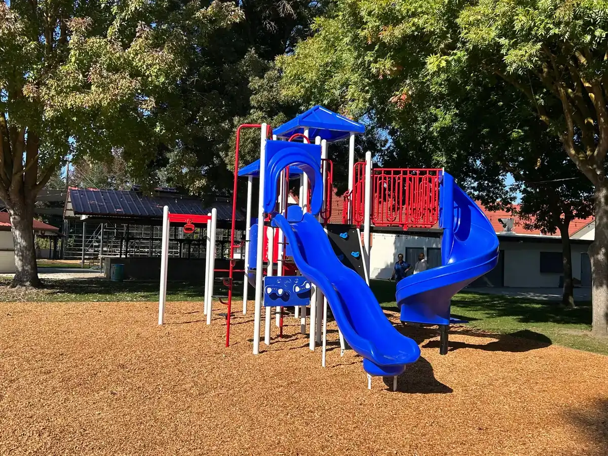 Newly installed playground with blue slides and engineered wood fiber surfacing