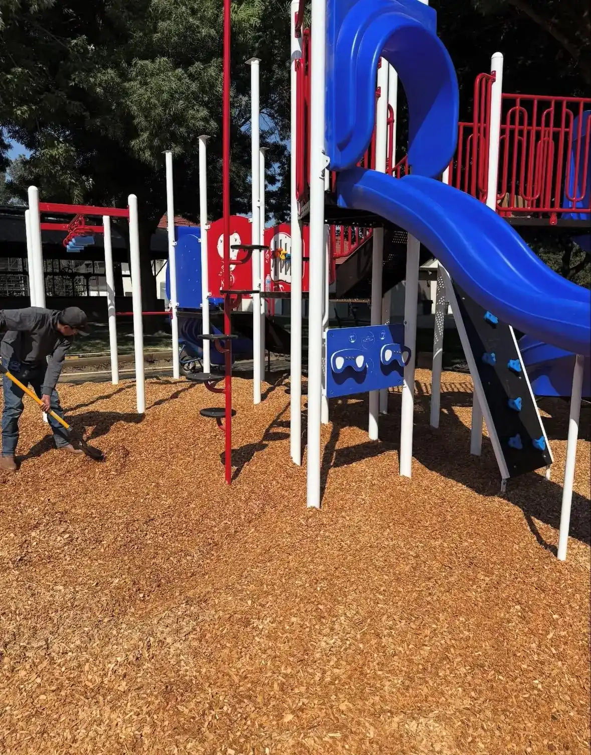 Crew spreading surfacing beneath a new red and blue play structure